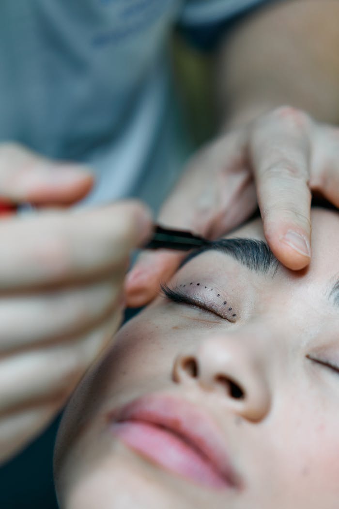 Close-up of a surgeon preparing for a blepharoplasty procedure marked on a woman's eyelid in a clinic.